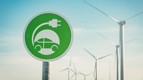 Electric car charge sign with wind turbines on background